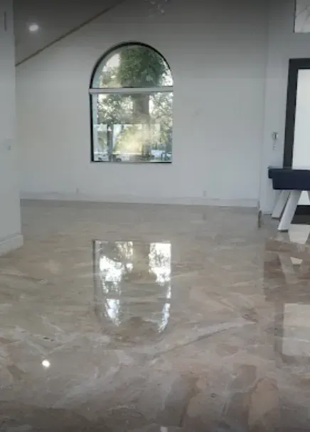 Empty room with glossy marble floor and arched window letting in daylight