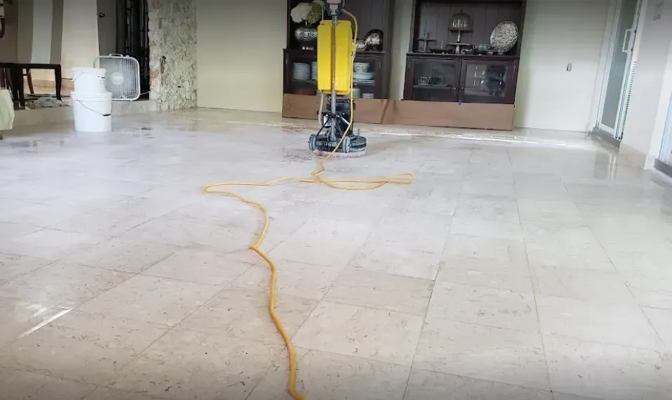 Yellow floor-cleaning machine on a tiled floor with a cord trailing across a living room.