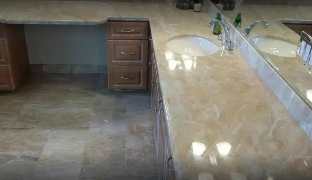 Bathroom vanity with stone countertop, sink, mirror, and small drawers beside tiled floor.