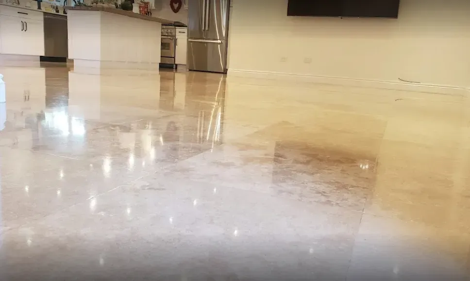 Shiny wet floor in an empty indoor room with kitchen cabinets and appliances in the background