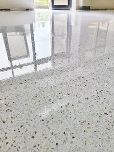 Polished speckled floor reflecting large window frames and bright daylight