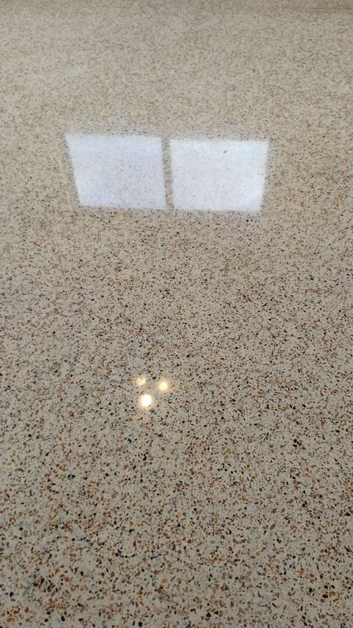 Speckled beige countertop with a bright white rectangular reflection near the top center