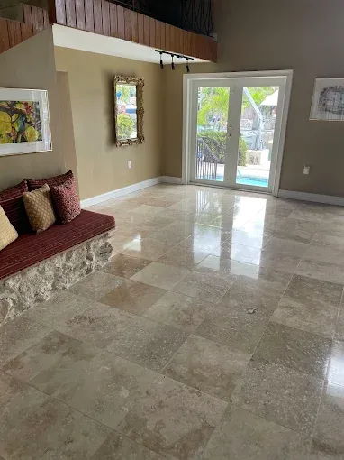 Bright living room with marble floor, built-in bench, wall art, and glass doors to a sunny patio