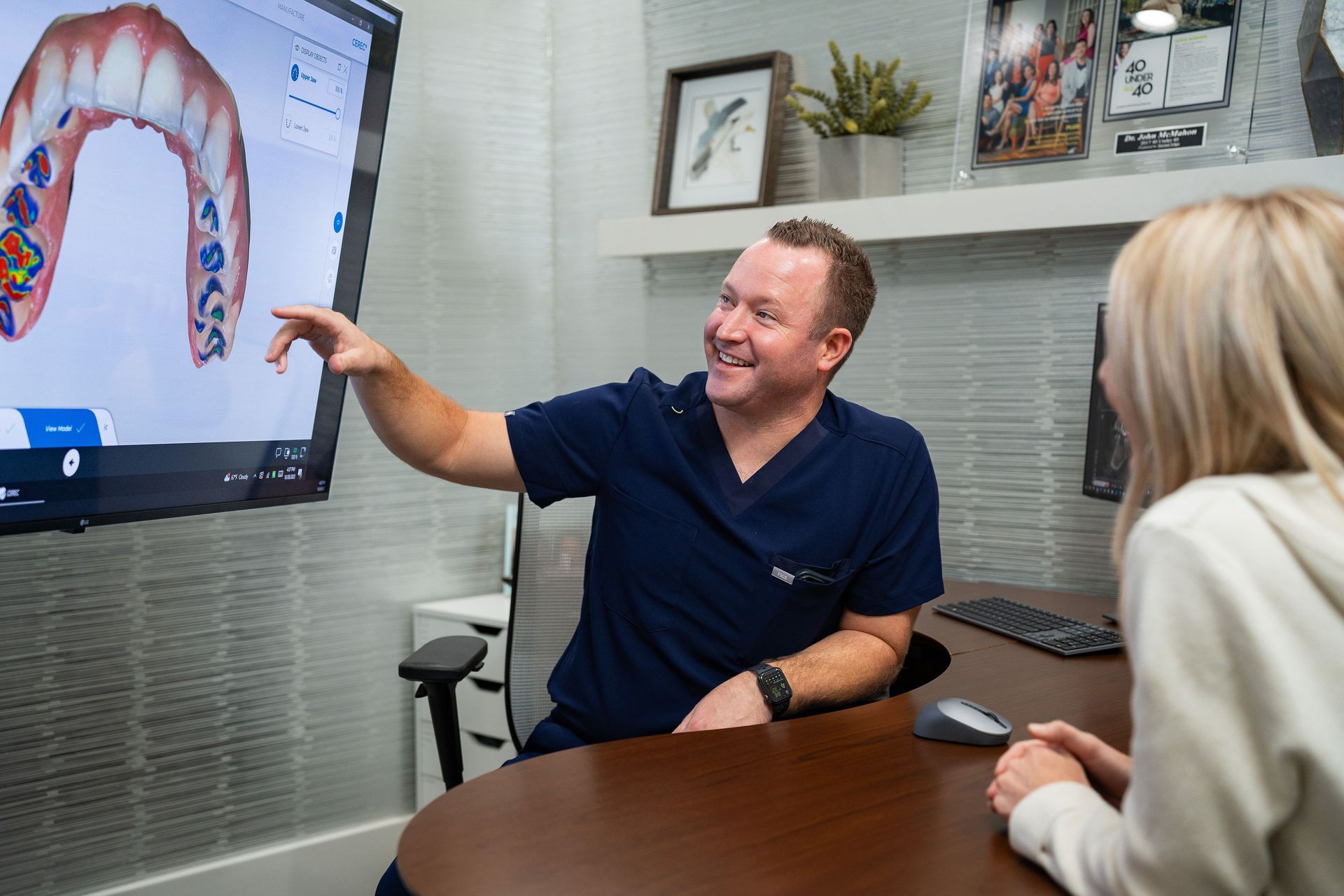 Dr. McMahon pointing at 3D teeth scan on screen, explaining to a patient wanting a smilemakeover.