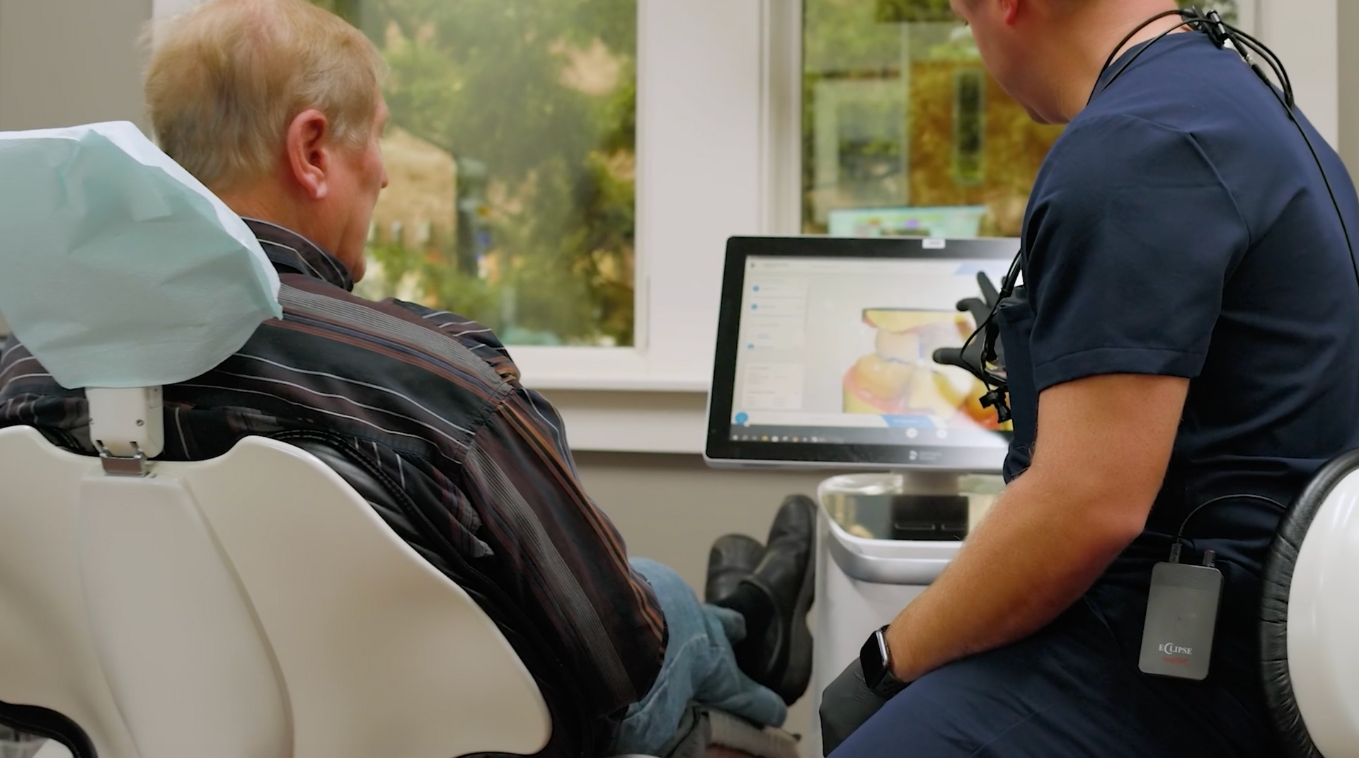 Dr.McMahon showing patient a digital image of teeth on a monitor in a dental office.