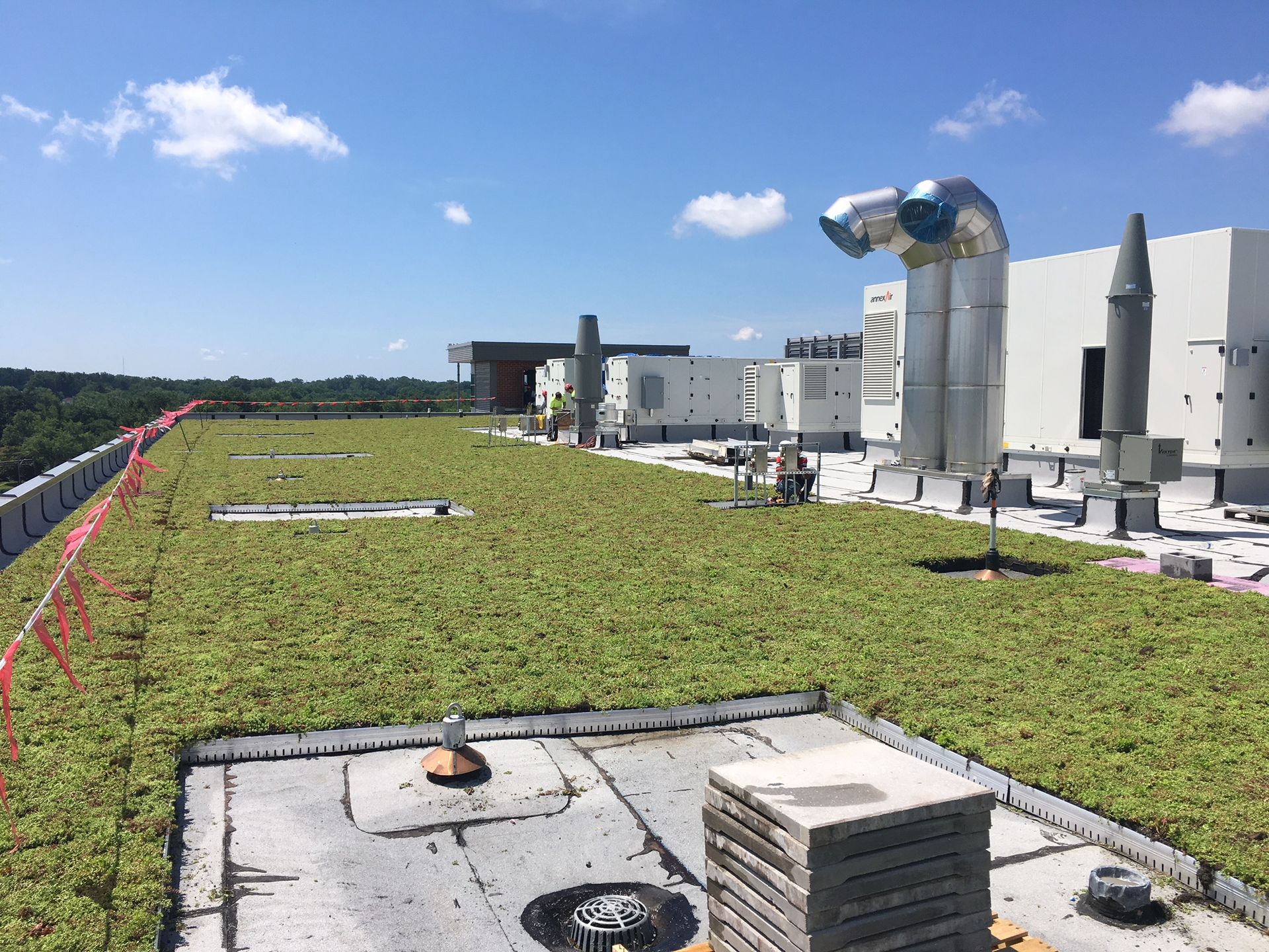 Green roof on a building with ventilation equipment and a cloudy sky.
