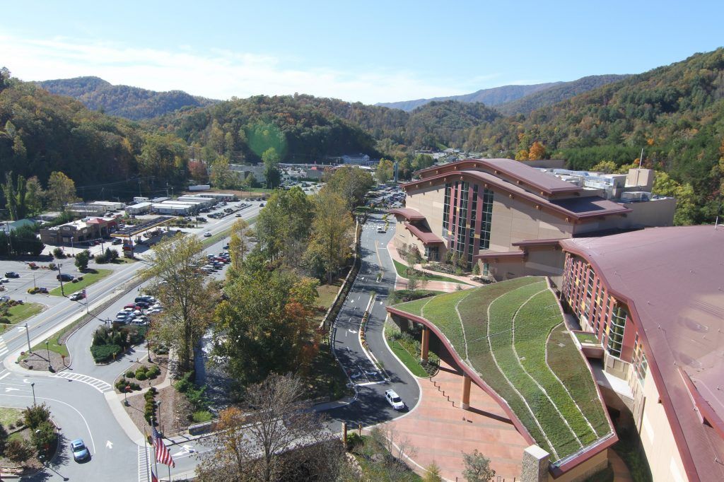 An aerial view of a resort with a green roof, road, and mountains in the background.