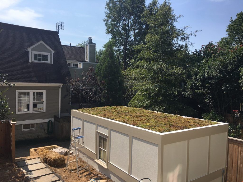 A building with a green roof, tan walls, and a small window, viewed from an outd