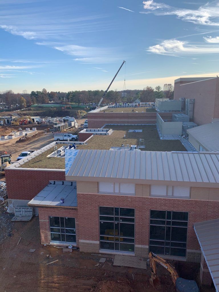 Construction site with crane, brick building, blue sky, and a small excavator.