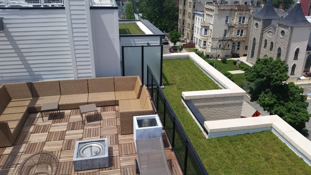 Rooftop patio with sectional seating, fire pit, green roof, and city views.