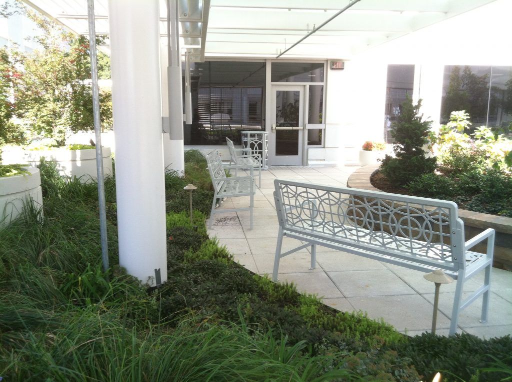 Outdoor patio with white benches, green plants, and a door.