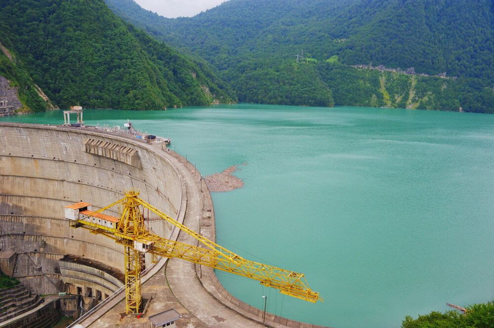 A Yellow Crane is Sitting on Top of a Dam Next to a Lake — Simon Dickson Excavations in Bowral, NSW