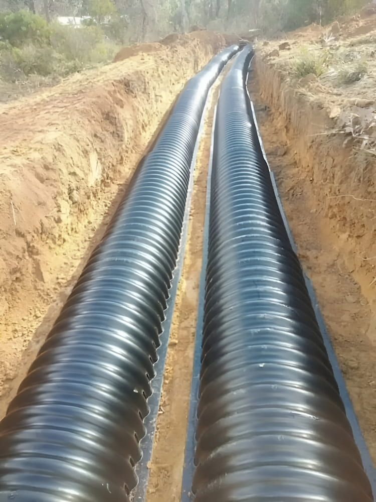 A Row of Black Pipes Going Down a Dirt Road — Simon Dickson Excavations in Moss Vale, NSW