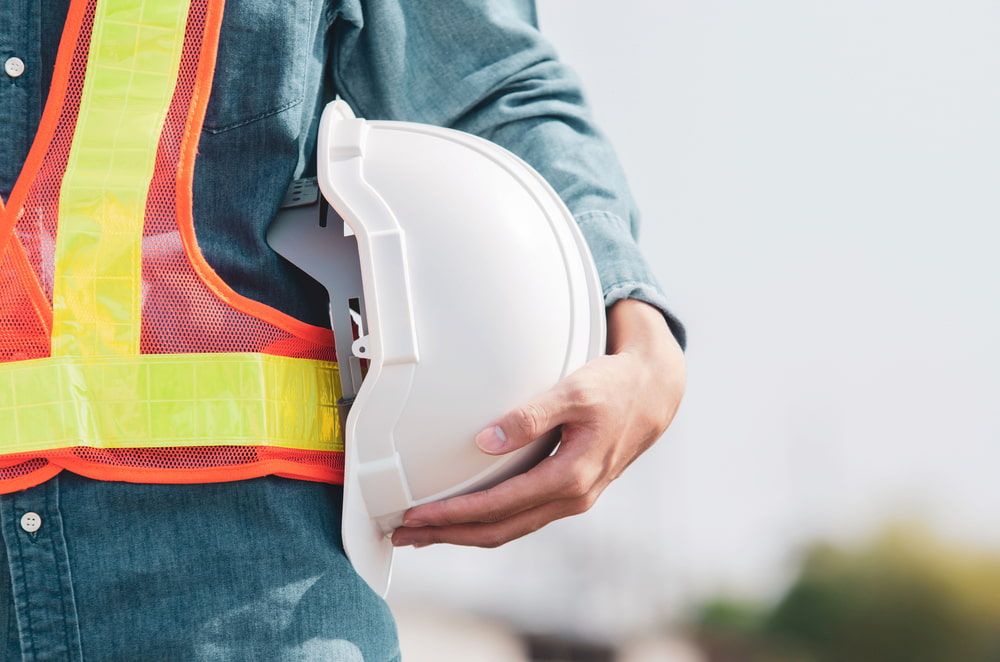 A Construction Worker is Holding a White Hard Hat in His Hand — Simon Dickson Excavations in Goulburn, NSW