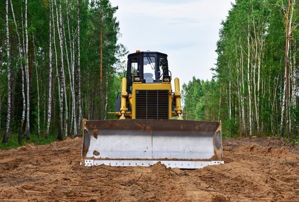 A Bulldozer is Moving Dirt in a Forest — Simon Dickson Excavations in Mittagong, NSW