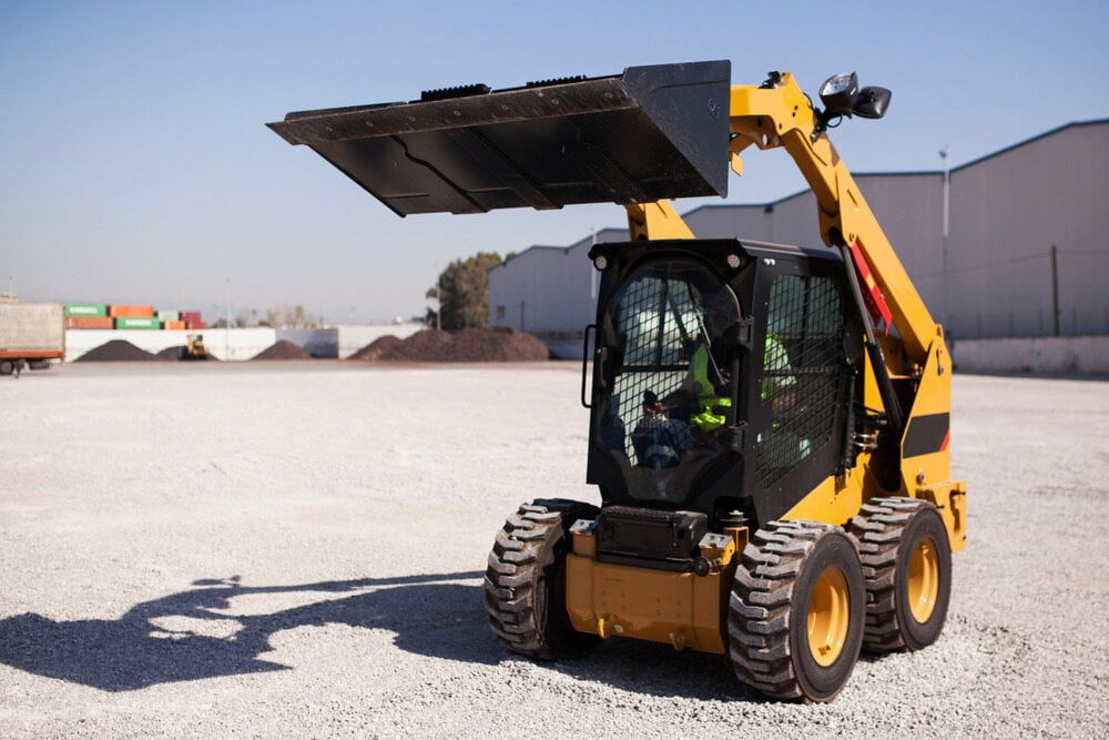 A Yellow Tractor is Parked in a Gravel Lot — Simon Dickson Excavations in Moss Vale, NSW