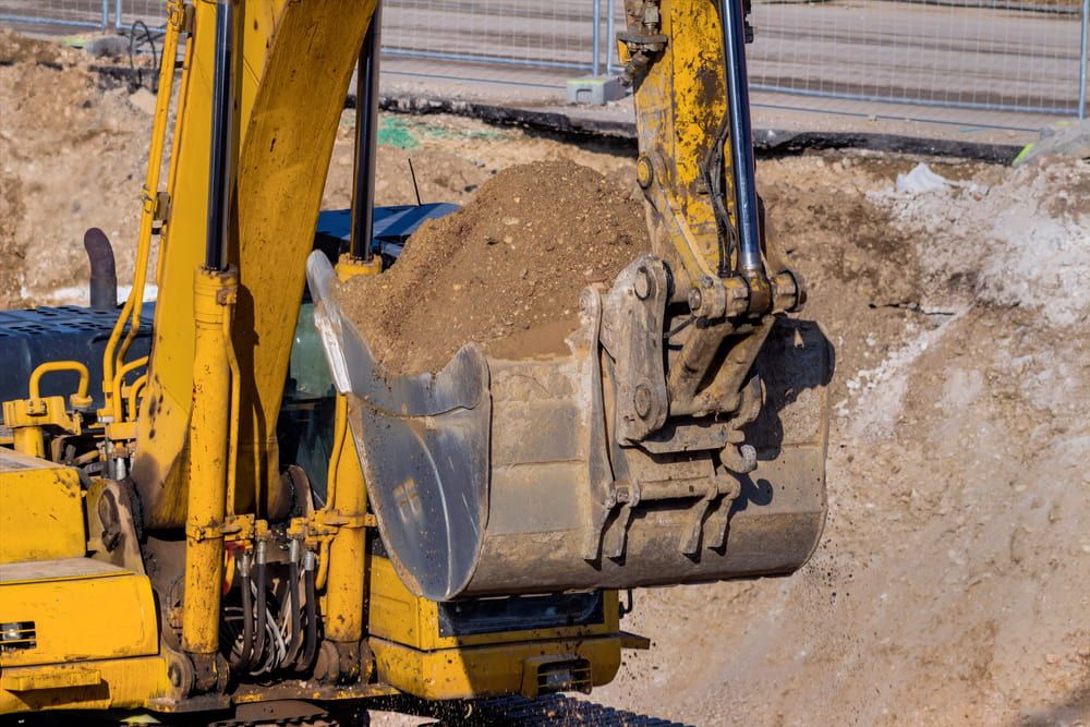 A Yellow Excavator is Loading Dirt Into Its Bucket at a Construction Site — Simon Dickson Excavations in Bowral, NSW