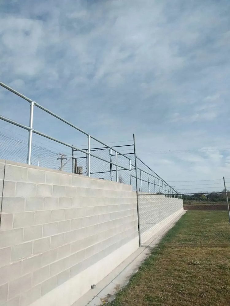 A Brick Wall with a Metal Railing on Top of It — Simon Dickson Excavations in Moss Vale, NSW