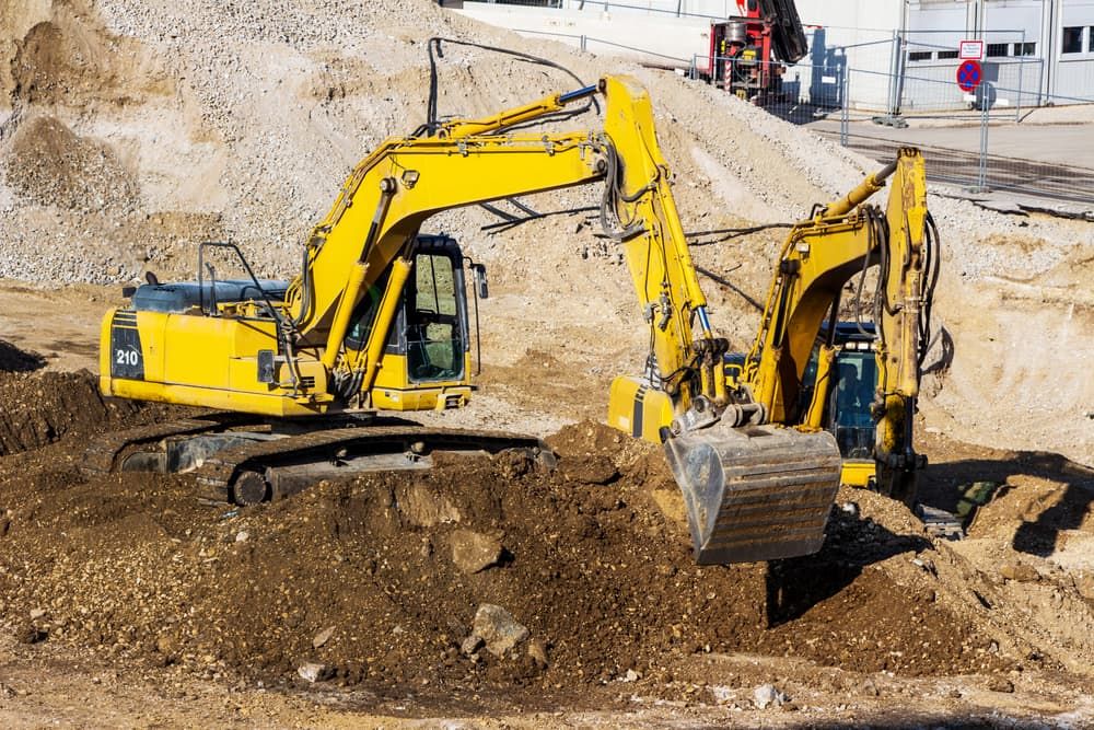 Two Yellow Excavators Are Working on a Construction Site — Simon Dickson Excavations in Moss Vale, NSW