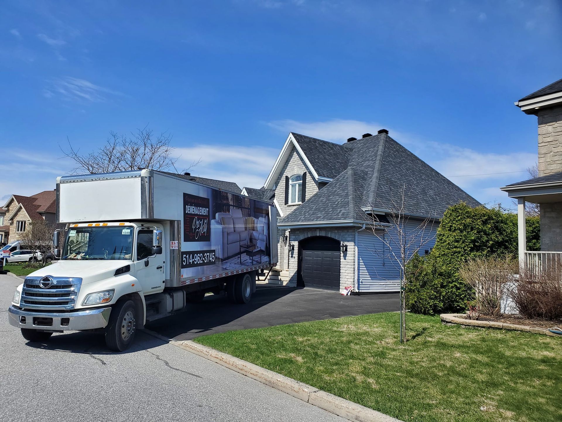 Un camion de déménagement blanc est garé devant une maison.