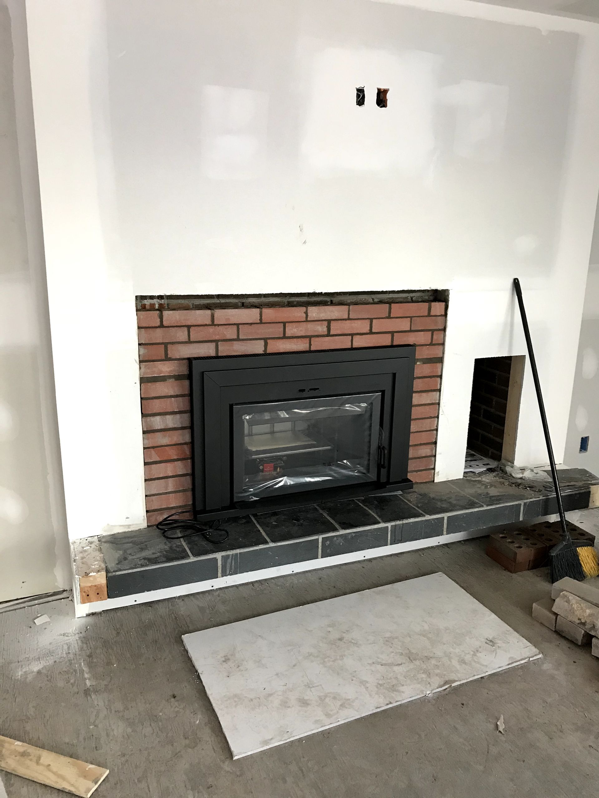 A brick fireplace is being built in a living room.