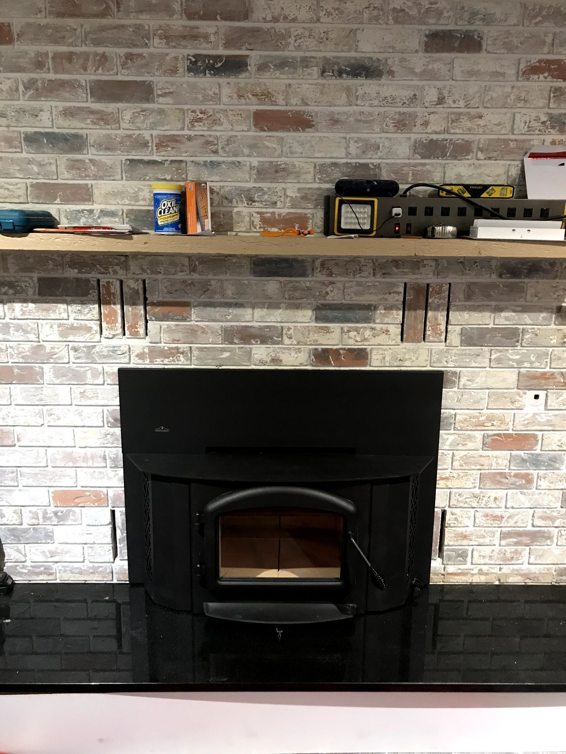 A black fireplace with a brick wall behind it
