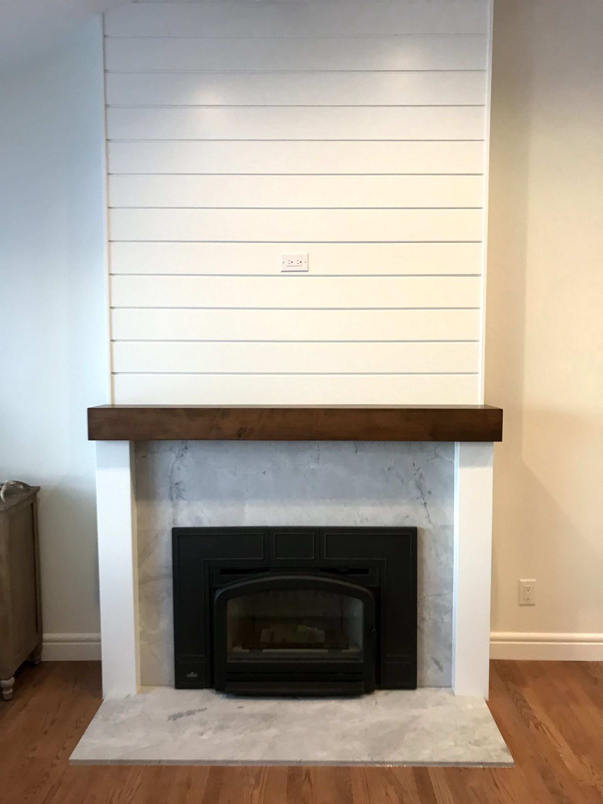 A fireplace with a wooden mantle in a living room.