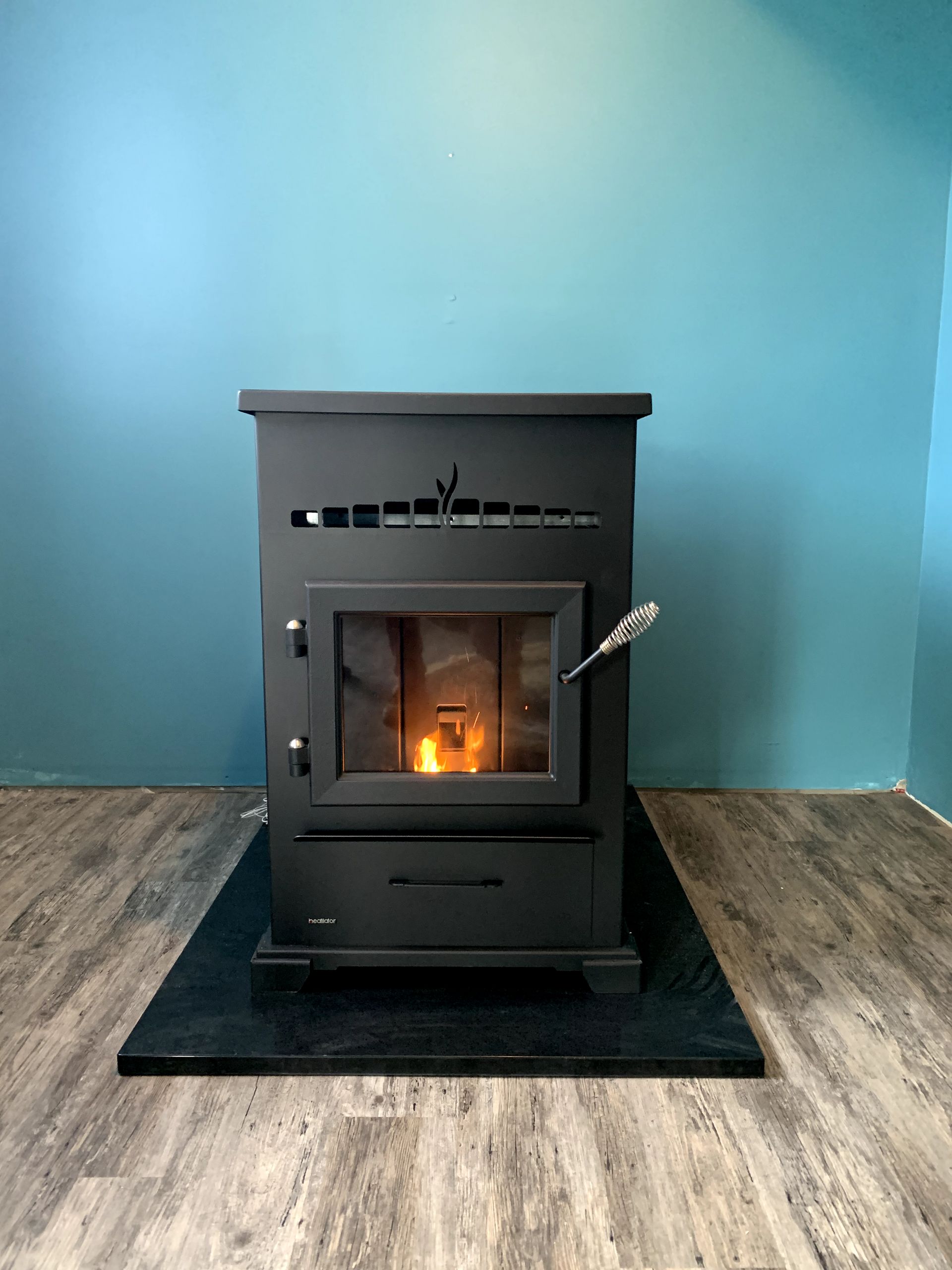 A black wood stove is sitting on a wooden floor in a room.
