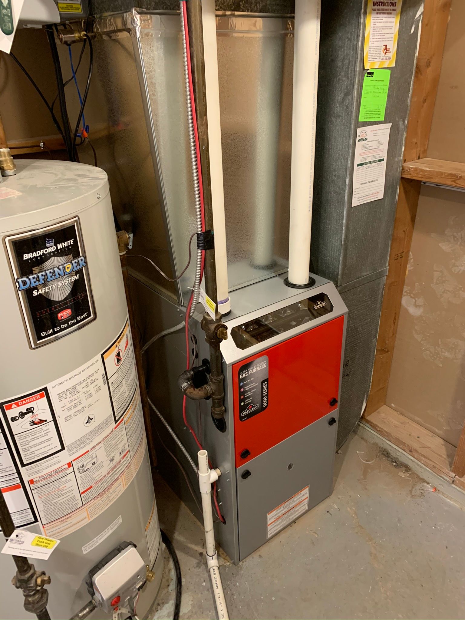 A gas heater and a water heater are sitting next to each other in a basement.