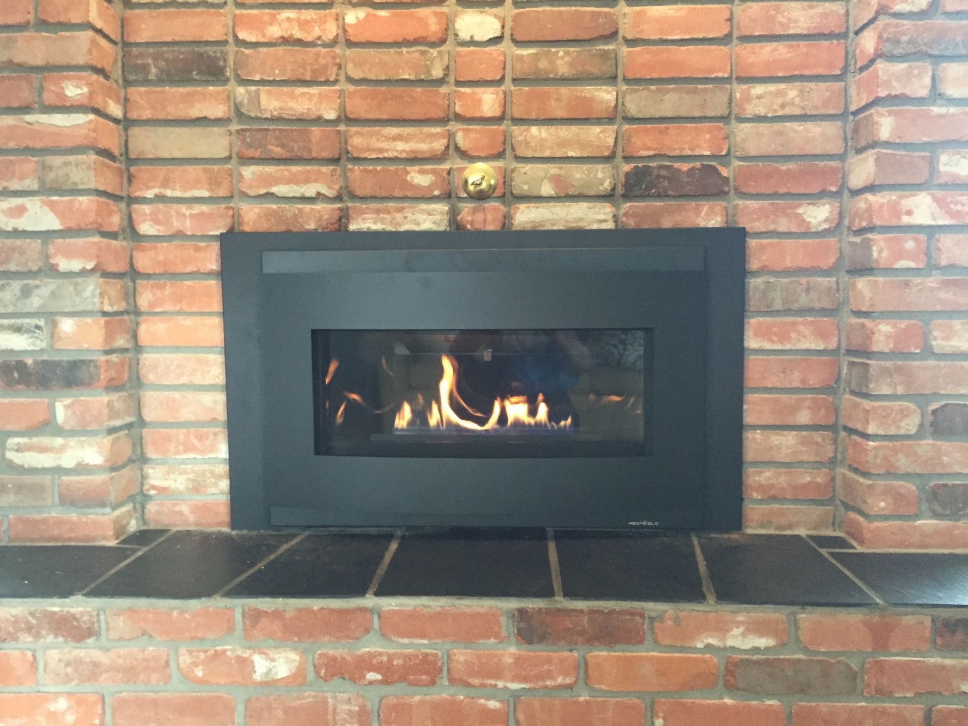 A fireplace with a black frame and a brick wall
