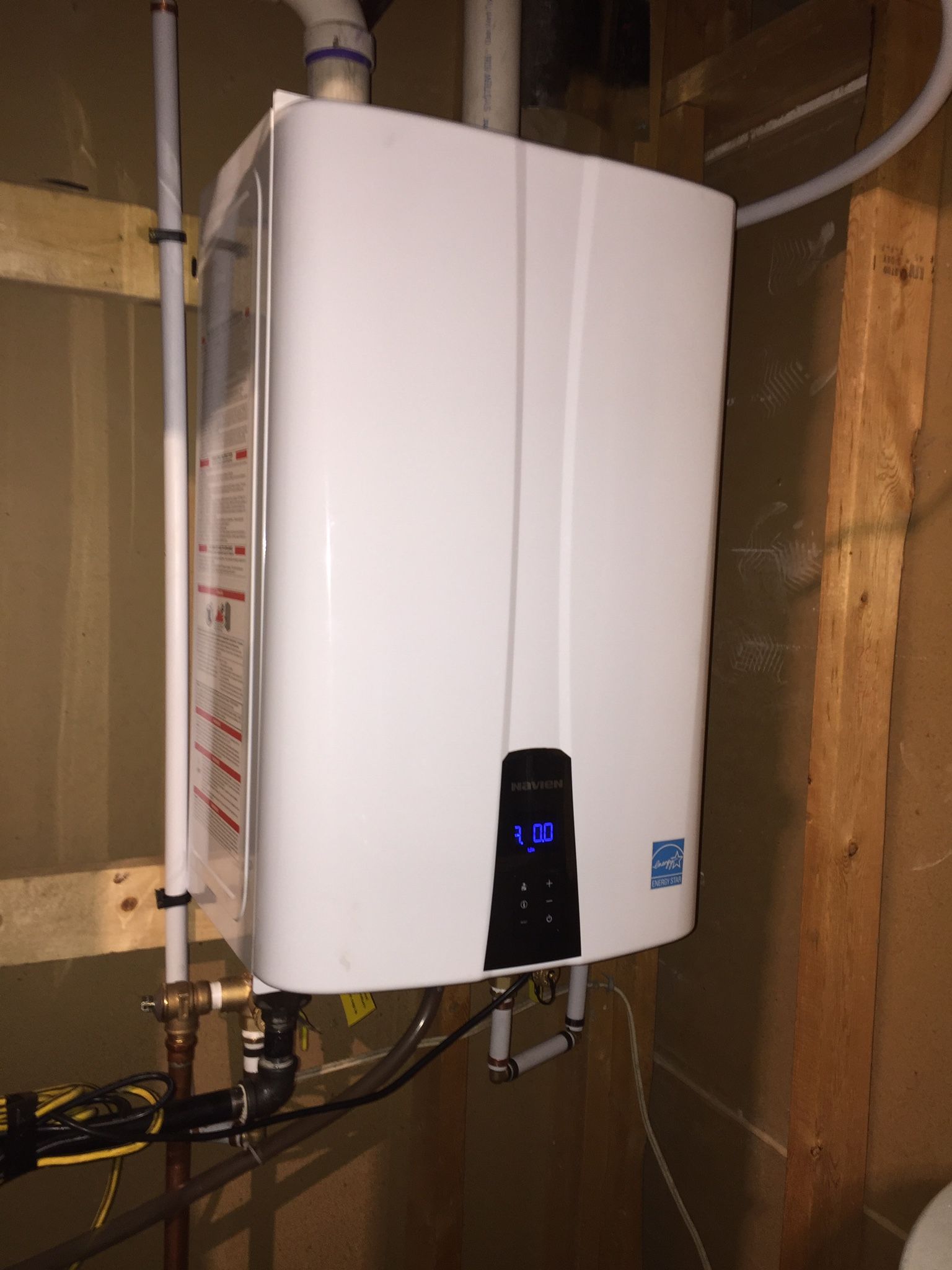 A white water heater is hanging on a wall in a room.