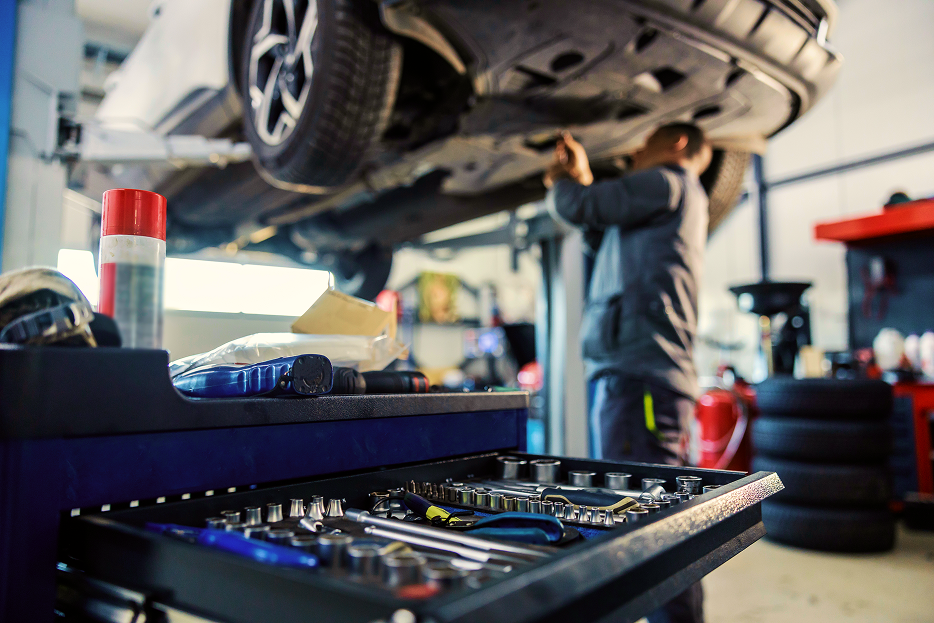 Technician working underneath vehicle lifted up in garage | RTS Tire & Auto Repair