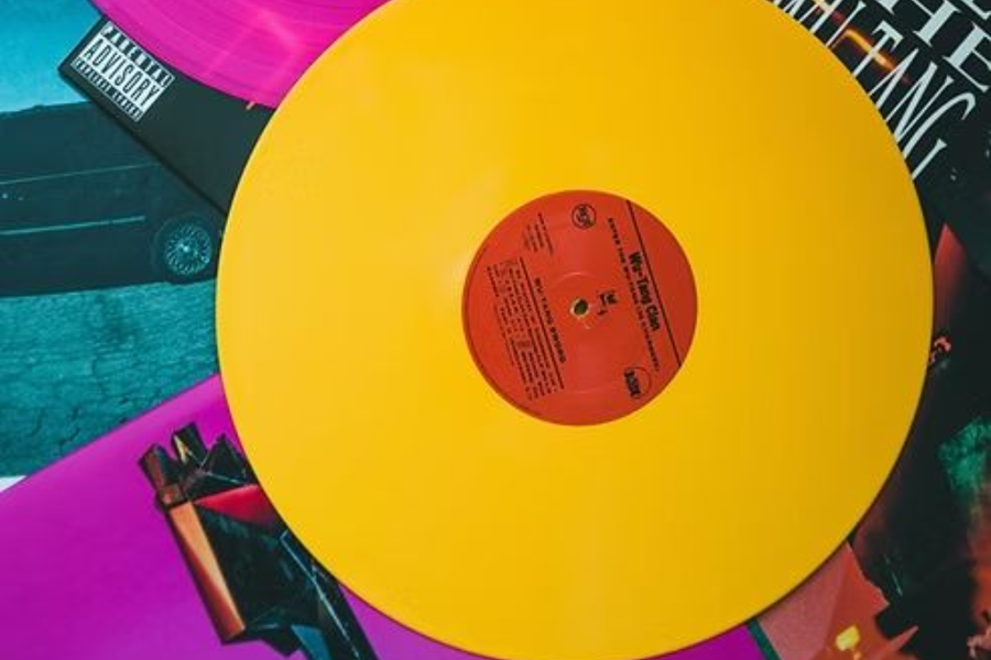 Bright yellow vinyl record with orange label on a colorful abstract background