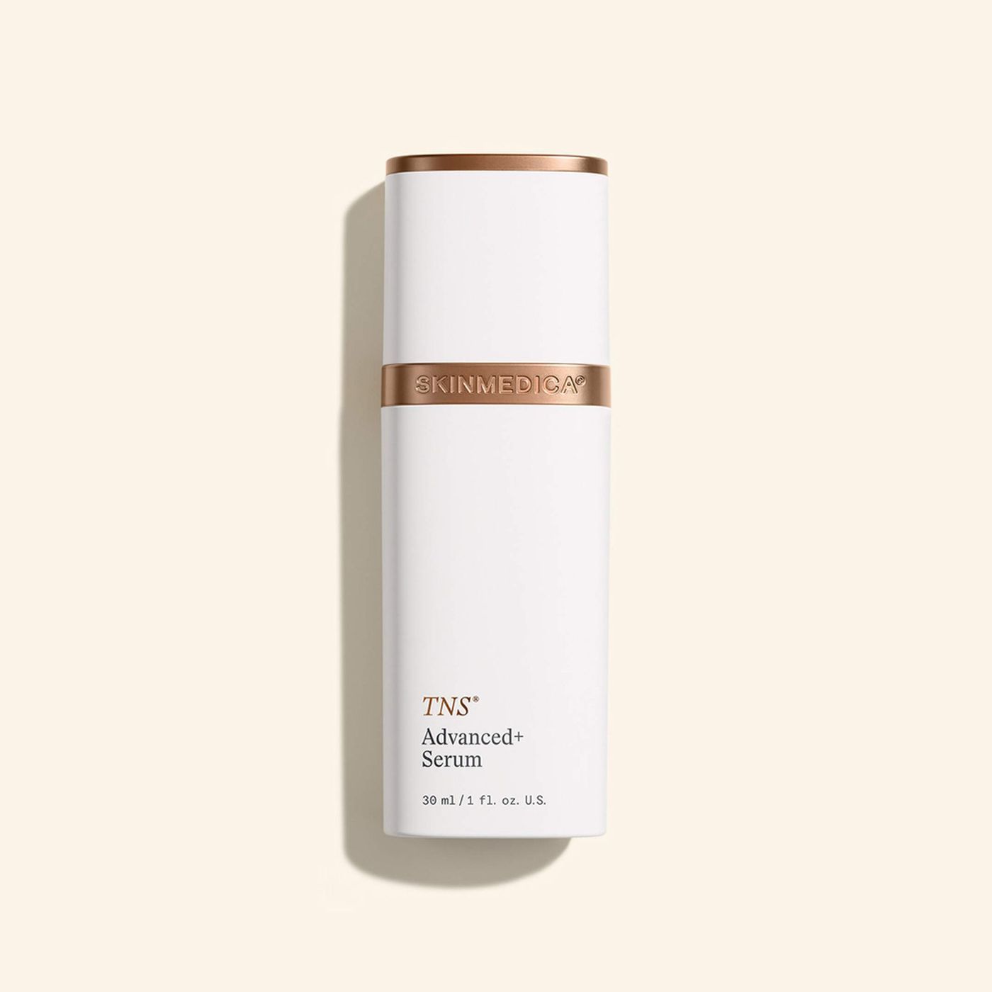 White cylindrical skincare bottle with gold accents on a beige background