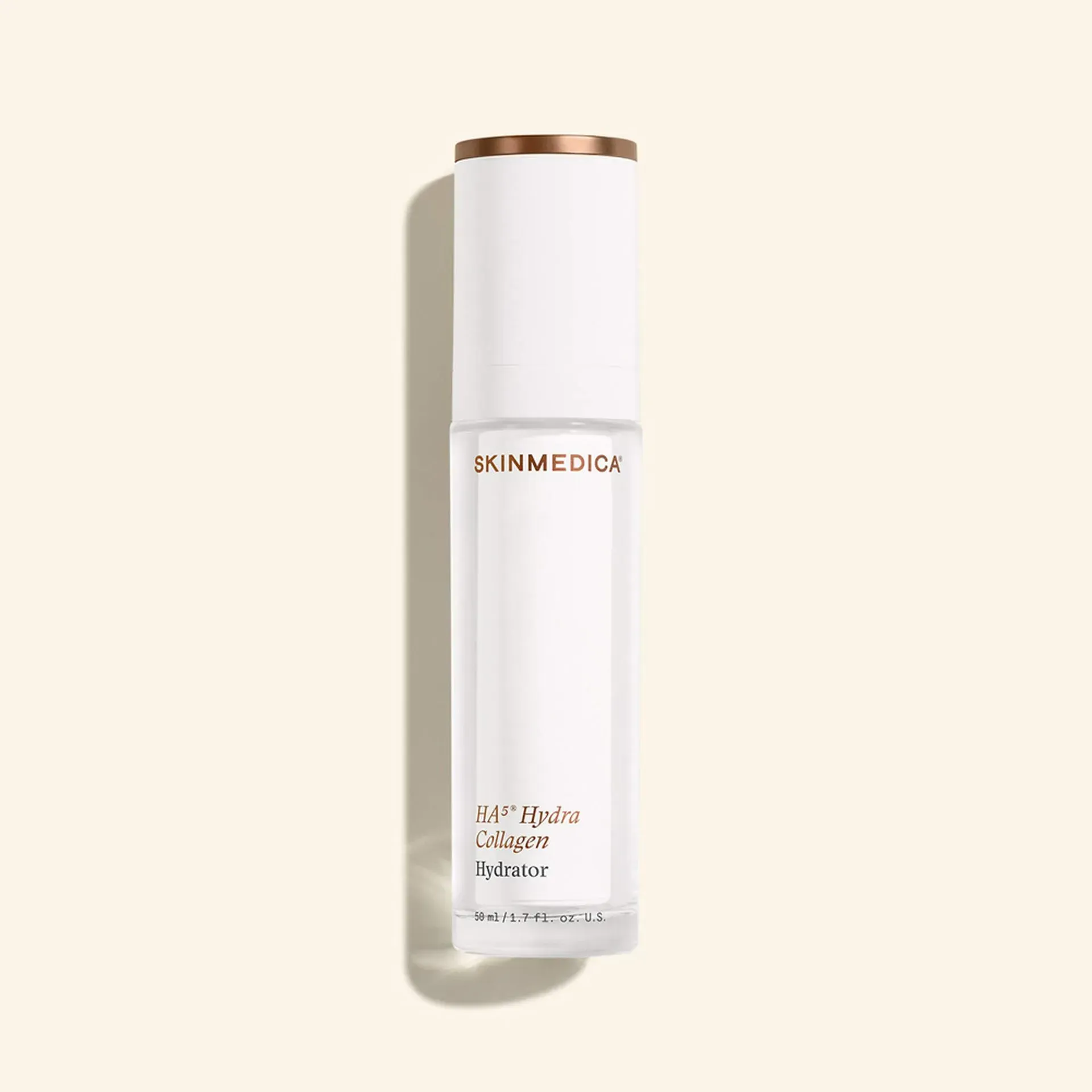 White cylindrical skincare bottle with gold cap on a light beige background