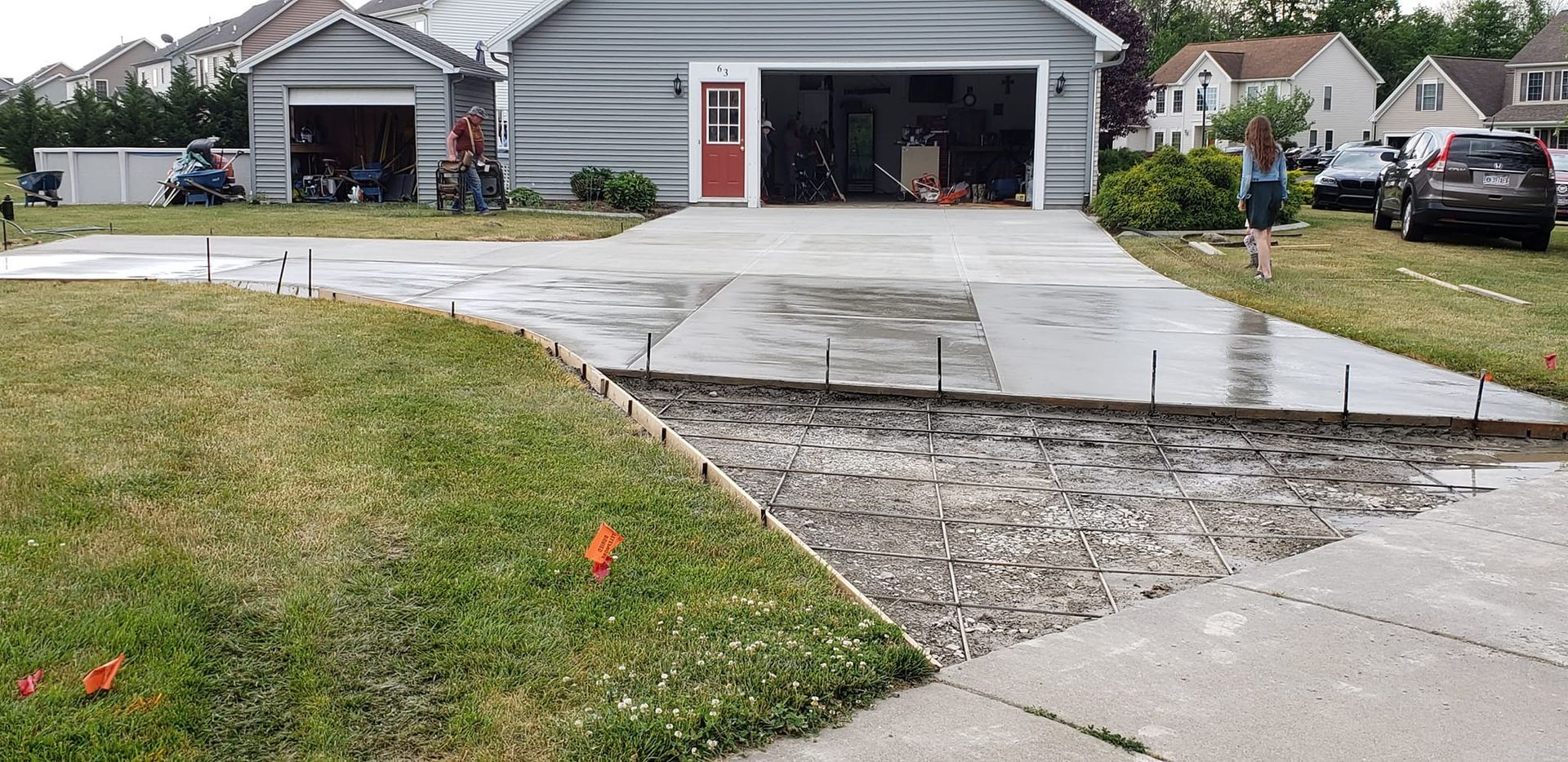 Driveway construction: fresh concrete, exposed gravel, and a garage.