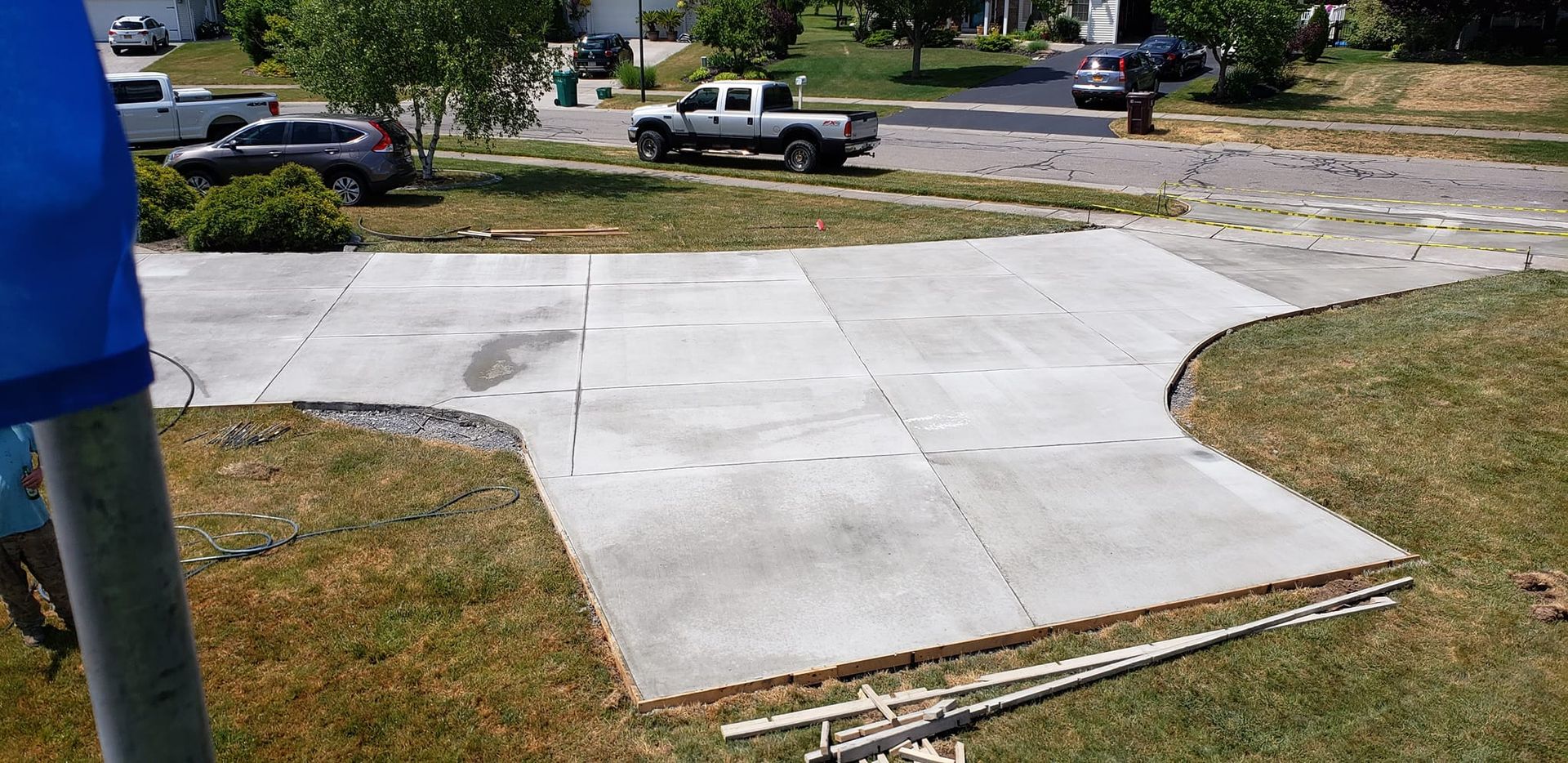 A freshly poured concrete driveway with a curb-like edge, in front of a house.