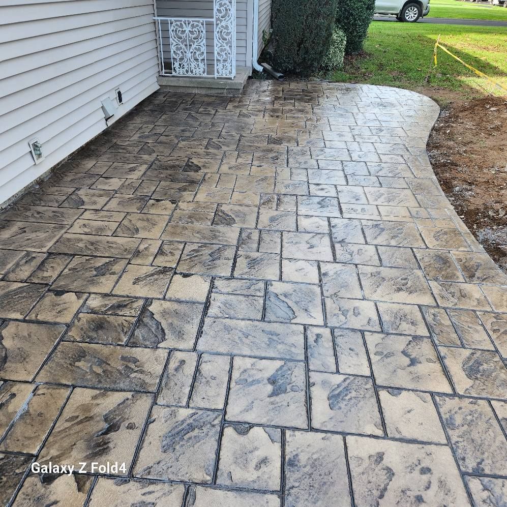 Stamped concrete patio with a stone pattern next to a house.