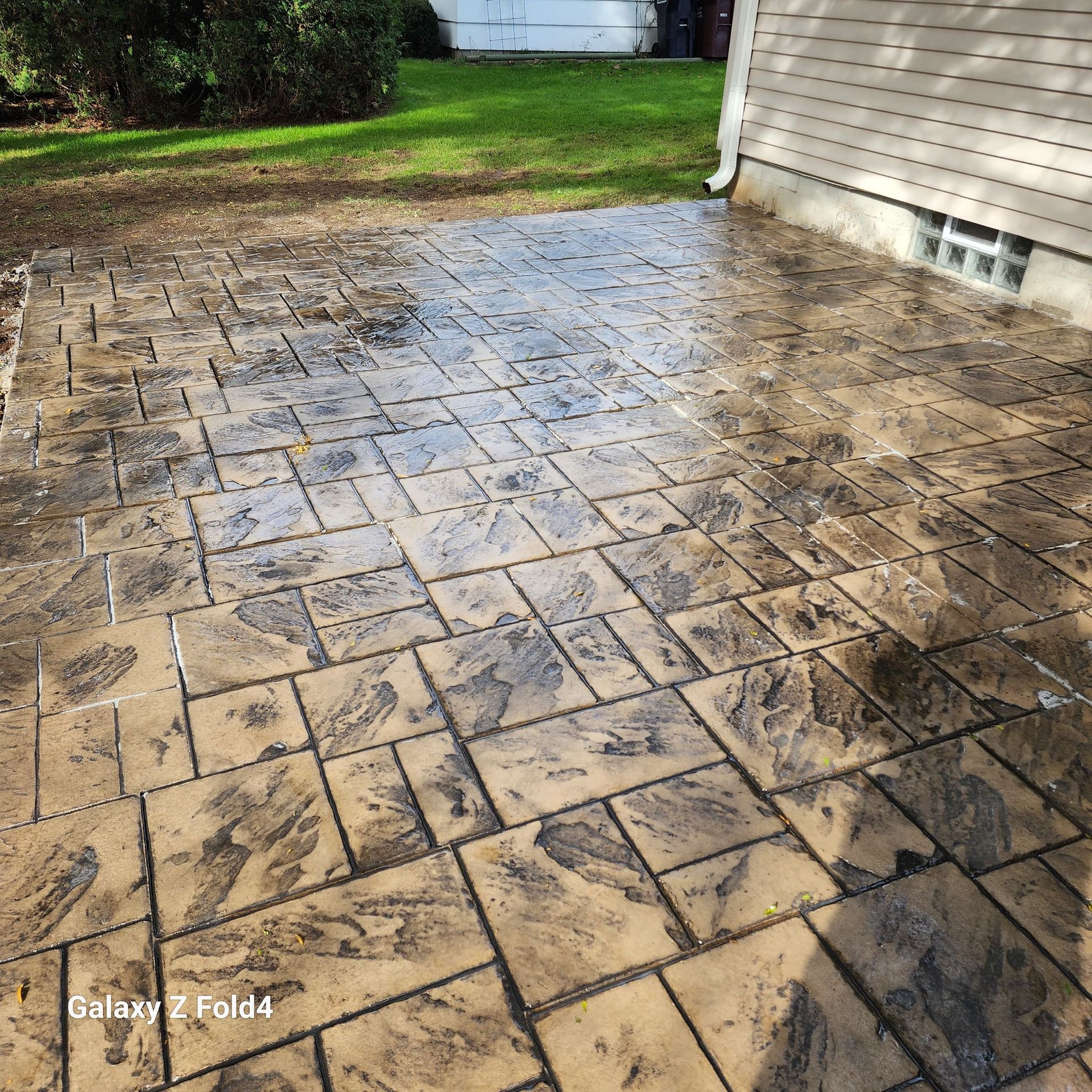 Stamped concrete patio with a textured pattern and a house in the background.