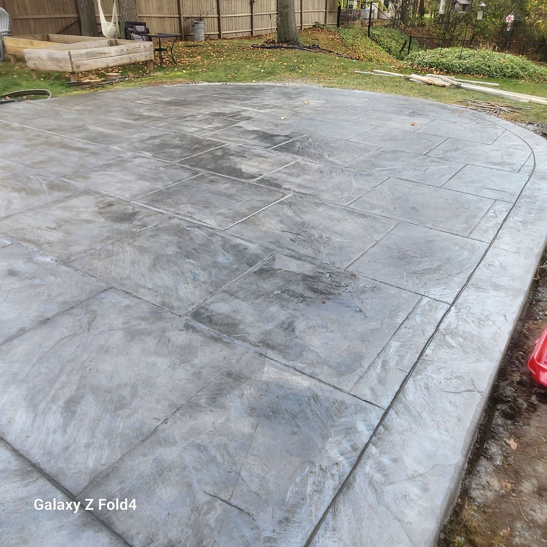 Gray concrete patio with textured surface. Outdoor setting with a curved edge.