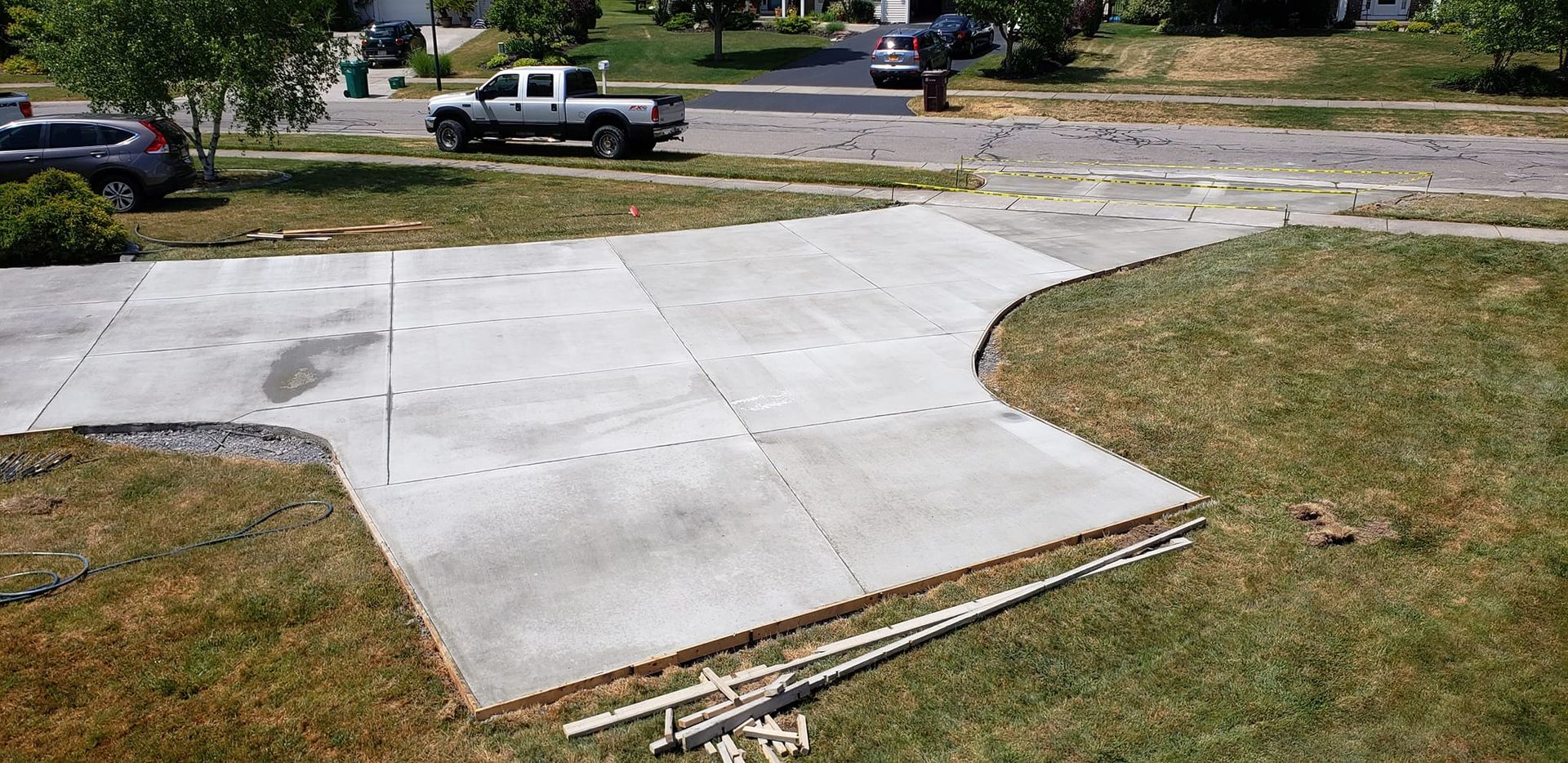 Newly poured concrete driveway with a truck driving down the street in the background.