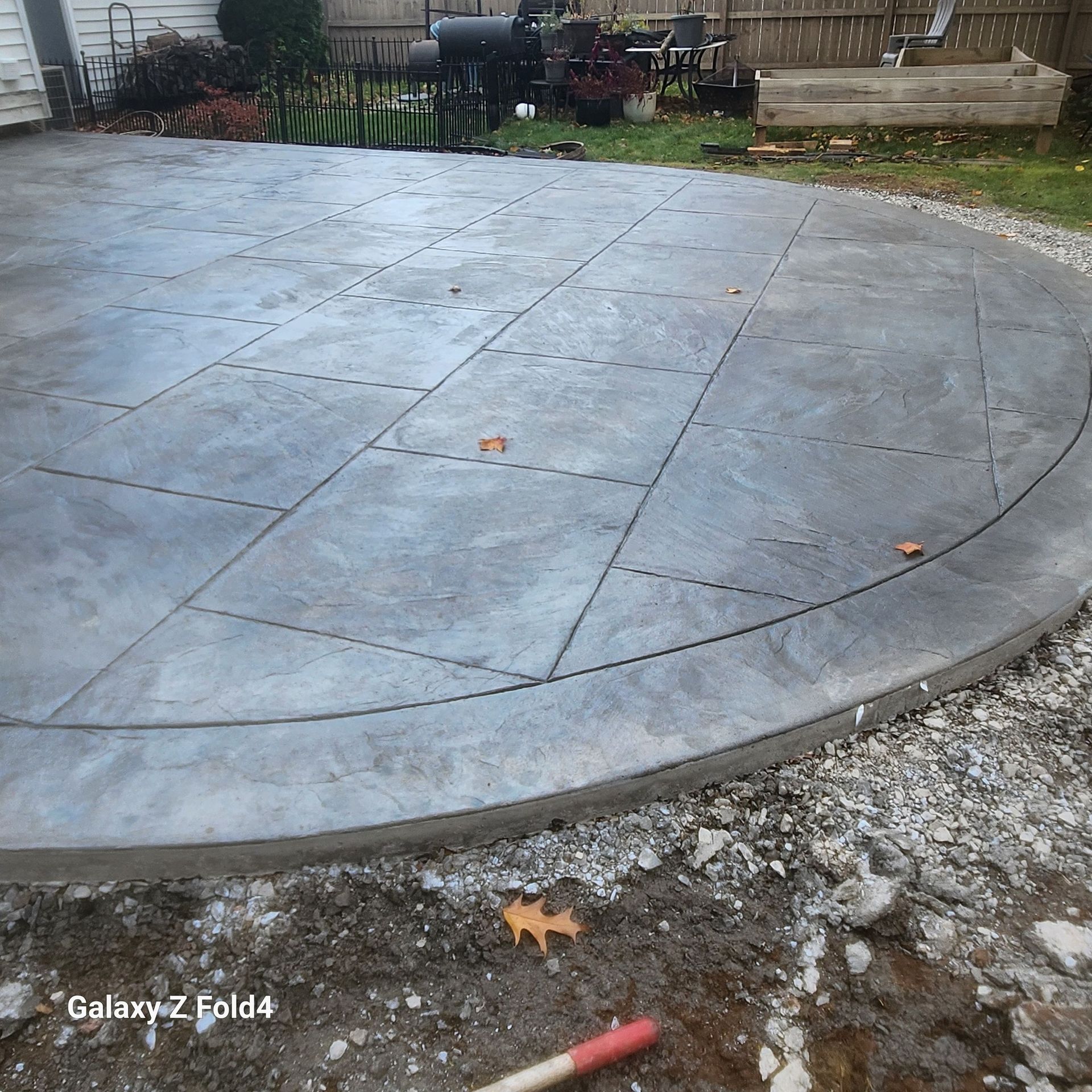 Gray concrete patio with rectangular and curved sections, with exposed edge, outdoor setting.