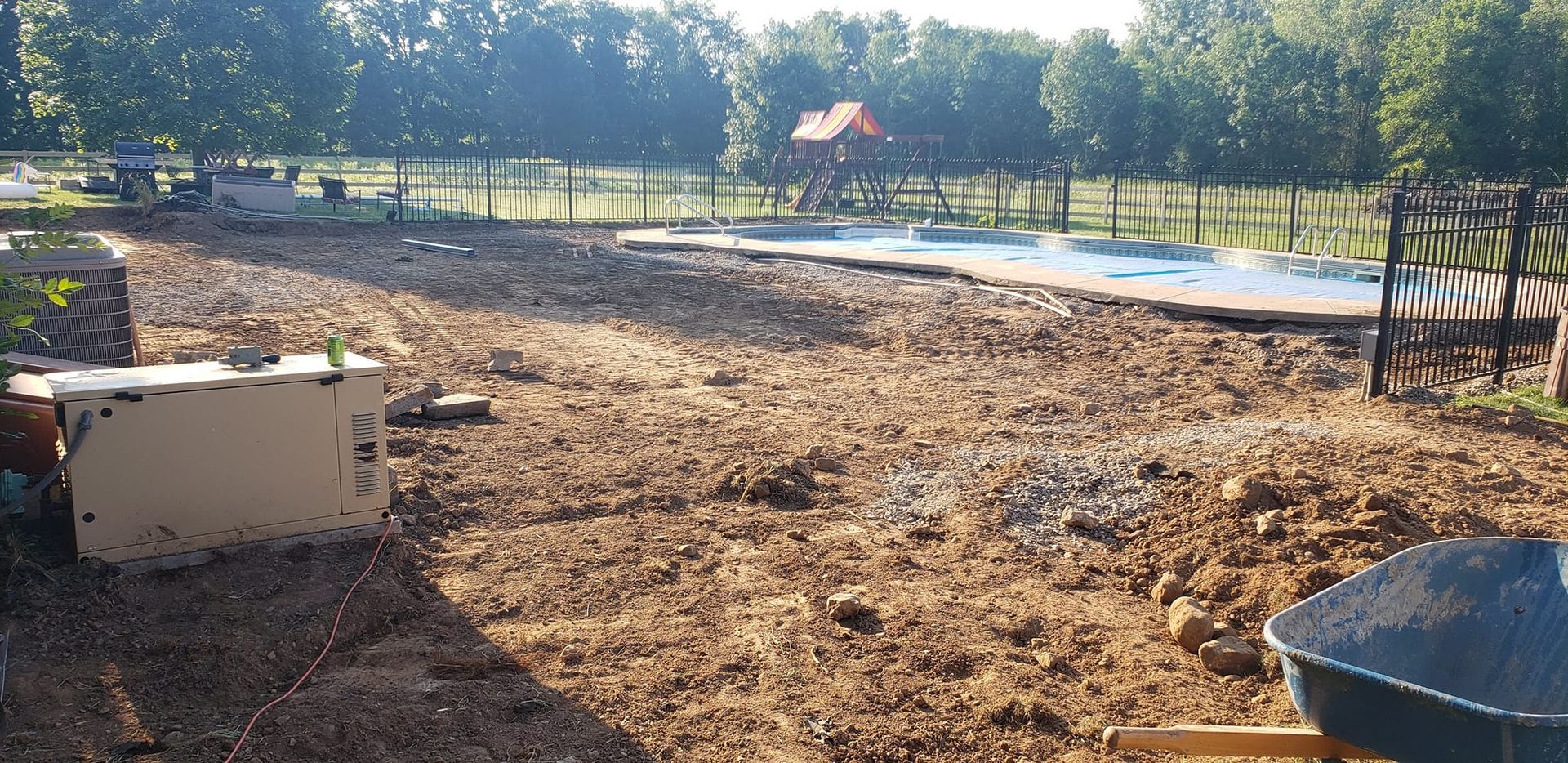 Dirt construction site with equipment and a playground in the background. Sunny day.