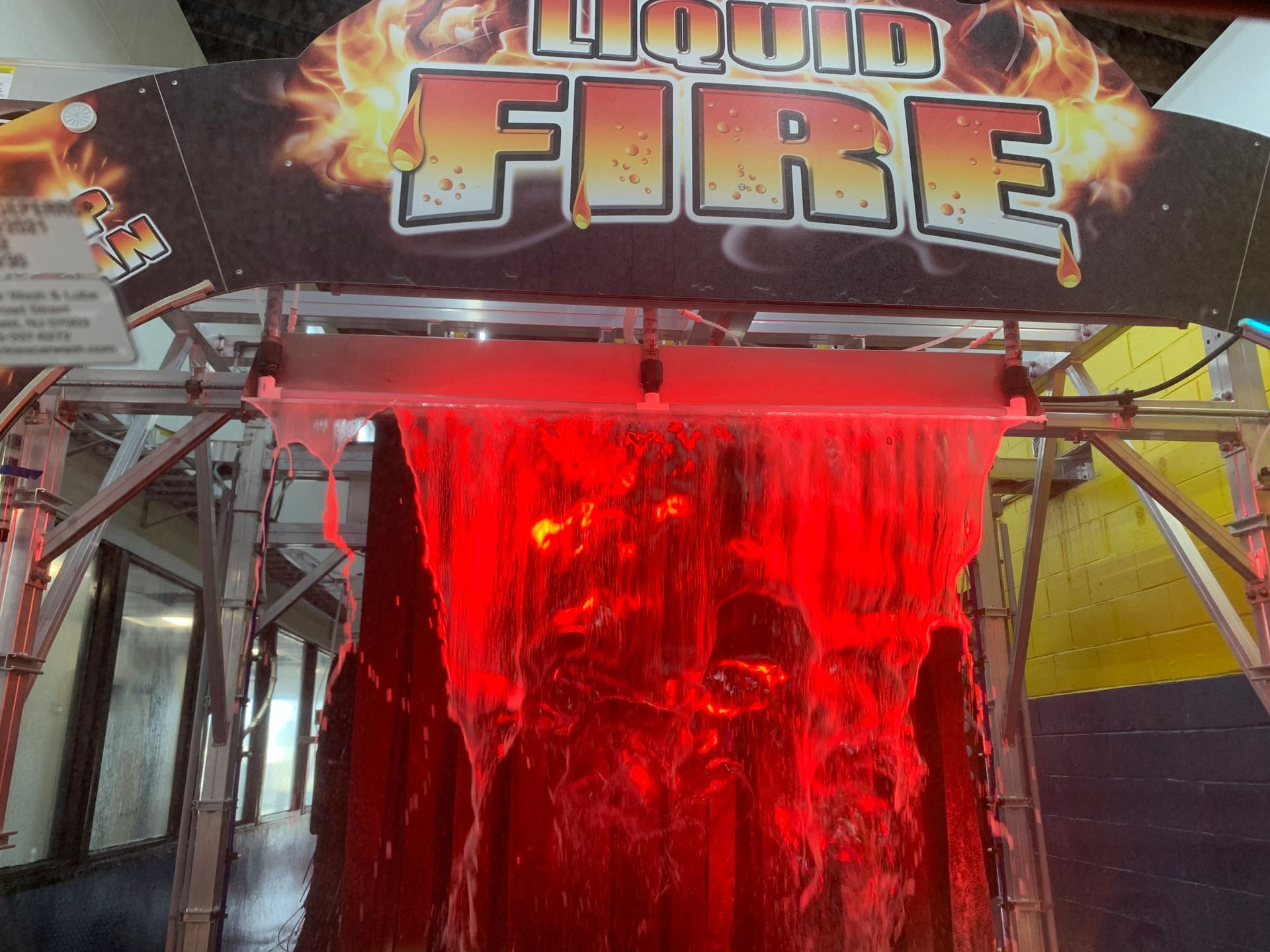 Red-lit liquid fire fountain display with glowing flames and metal framing at a fair booth