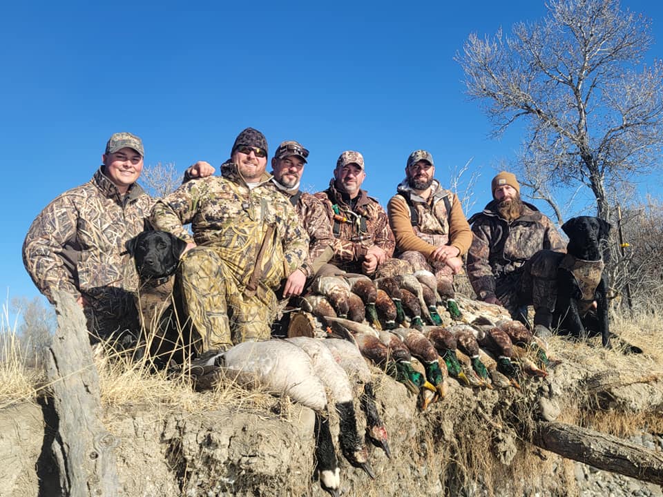A group of hunters are posing for a picture with their duck trophies.