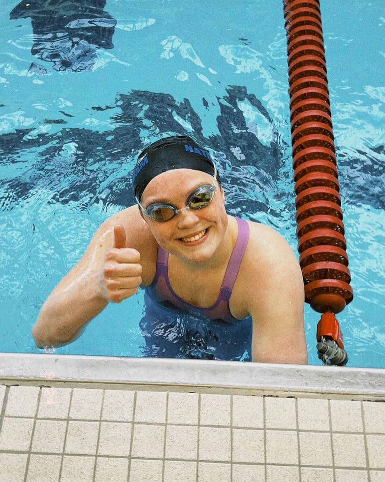 a swimmer smiles while in the pool and holding onto the wall