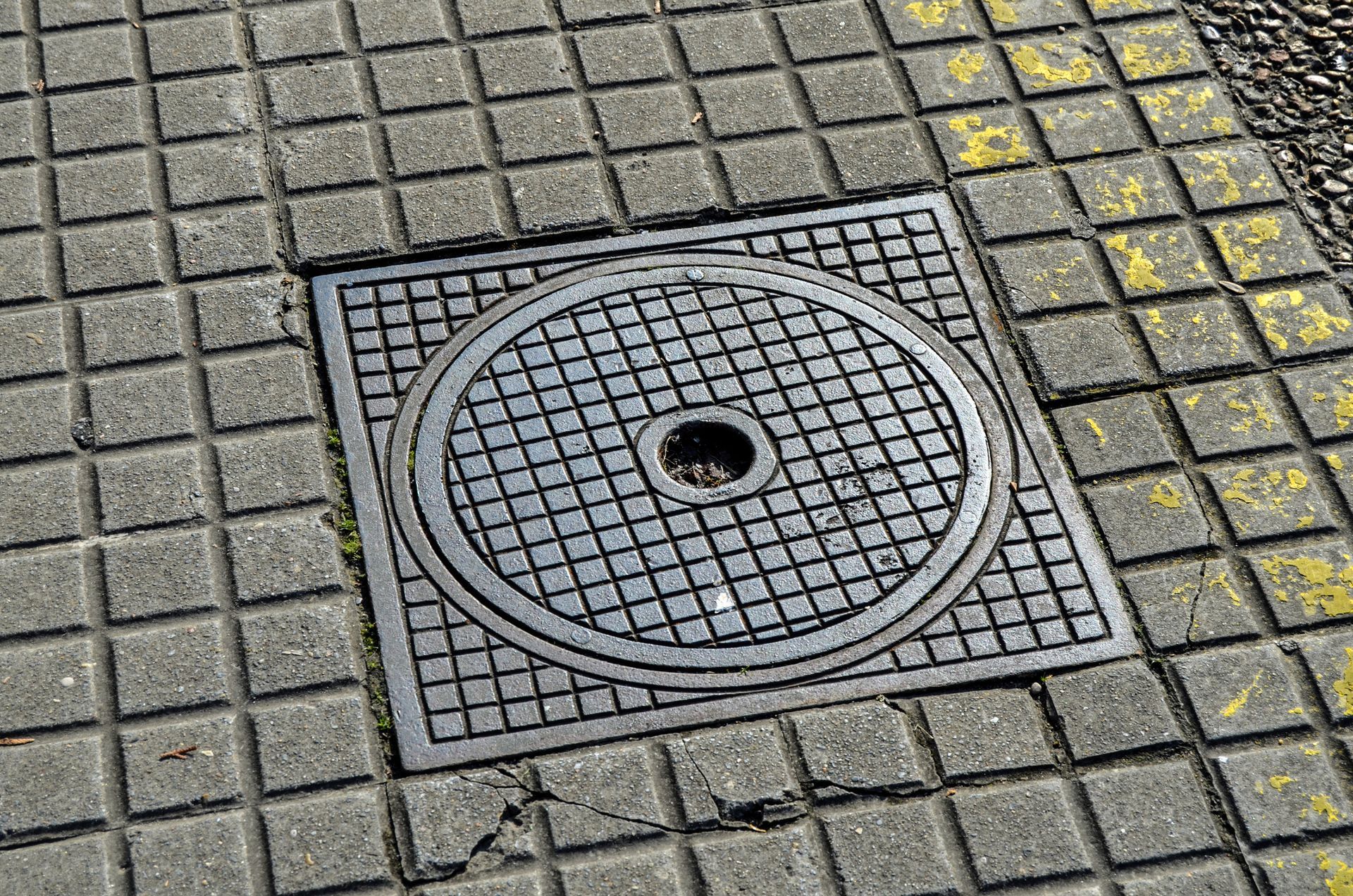 A manhole cover on a tiled floor with a hole in the middle
