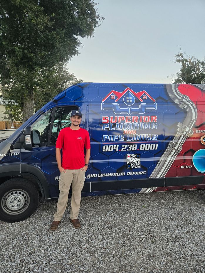 A person in a red shirt stands smiling in front of a blue van for