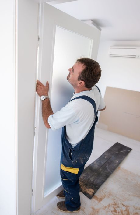 Carpenters installing glass door with a wooden frame