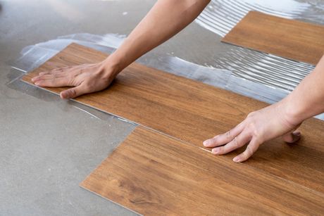 Vinyl installation by laying vinyl sheet tiles on notched trowel glue area